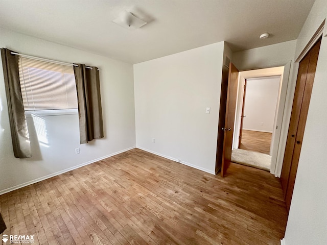 spare room featuring baseboards and wood-type flooring