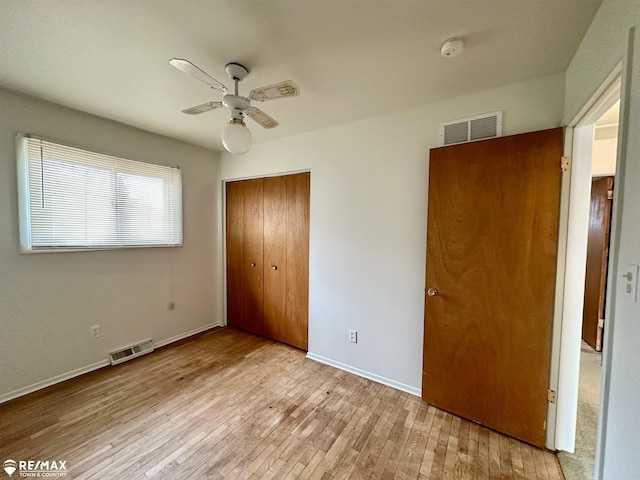 unfurnished bedroom with baseboards, visible vents, wood-type flooring, and a closet