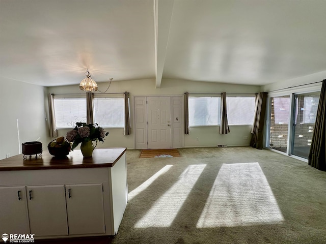 interior space featuring visible vents, light colored carpet, and vaulted ceiling with beams