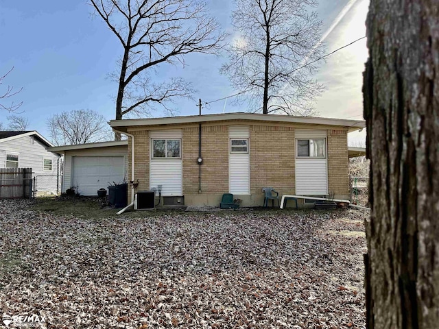 back of property with an attached garage, fence, brick siding, and cooling unit