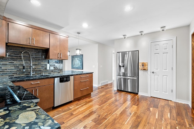 kitchen featuring visible vents, a sink, stainless steel appliances, light wood-style floors, and backsplash