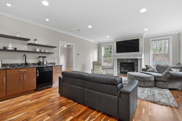 living room featuring a wealth of natural light, light wood-style flooring, crown molding, and a high end fireplace