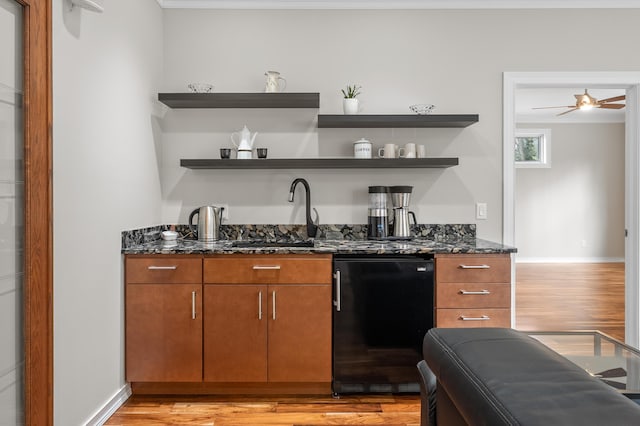 bar featuring light wood finished floors, ceiling fan, baseboards, refrigerator, and a sink