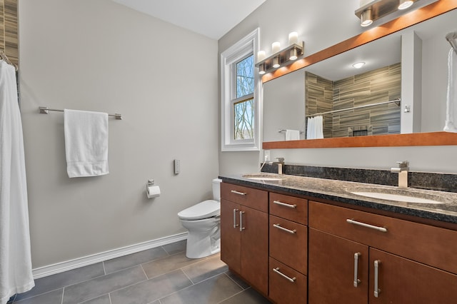 bathroom featuring tile patterned floors, toilet, baseboards, and a sink