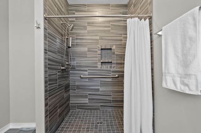 bathroom with baseboards and tiled shower