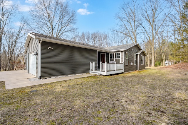 view of front of home featuring a deck, concrete driveway, a front yard, and a garage