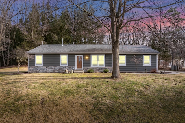 ranch-style home with a yard, stone siding, and entry steps