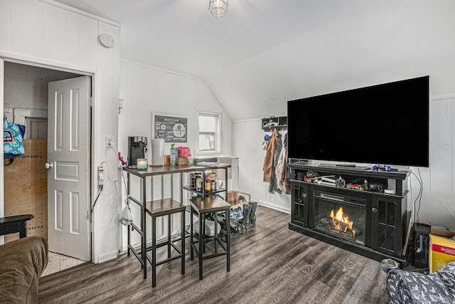 dining space with lofted ceiling, a lit fireplace, and wood finished floors