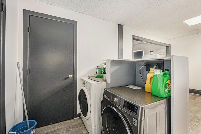 laundry room with washer and clothes dryer, baseboards, and wood finished floors