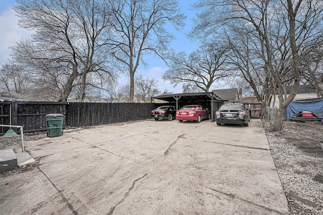 view of car parking featuring a carport, driveway, and fence