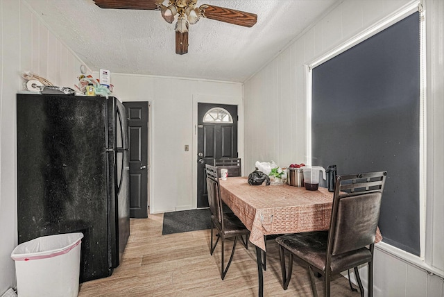 dining room featuring a textured ceiling, light wood-type flooring, and a ceiling fan