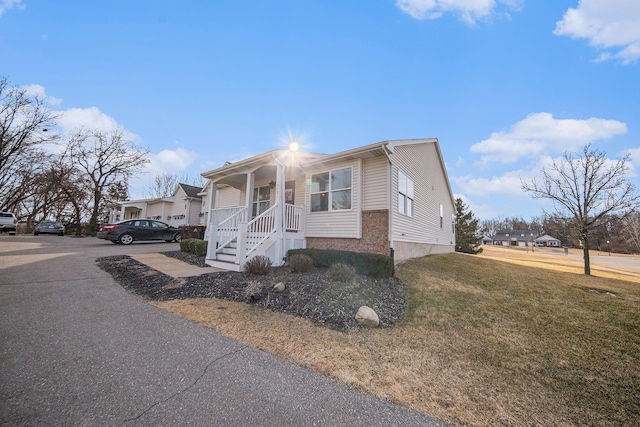 view of front of home featuring brick siding, covered porch, and a front yard