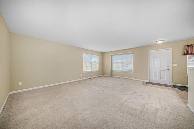 unfurnished living room featuring carpet flooring and baseboards