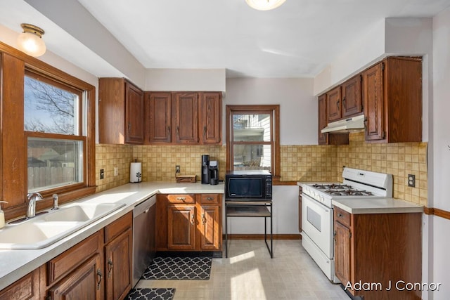 kitchen featuring gas range gas stove, a sink, under cabinet range hood, black microwave, and stainless steel dishwasher