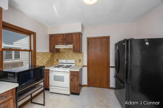 kitchen with under cabinet range hood, light floors, black appliances, and light countertops