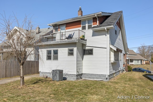 rear view of house featuring fence, a lawn, cooling unit, a chimney, and a balcony