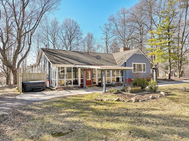 back of house featuring a patio, a chimney, a sunroom, and a hot tub