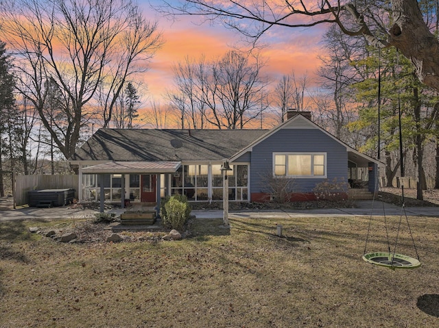 rear view of property with a yard, a sunroom, a chimney, and fence