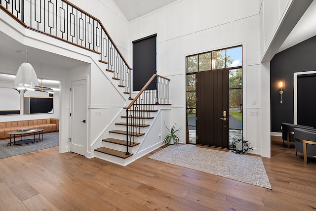 entryway featuring baseboards, high vaulted ceiling, stairs, and hardwood / wood-style flooring