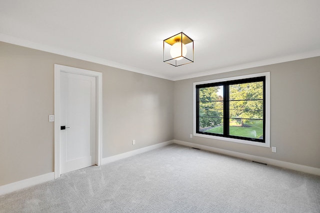 empty room with crown molding, light colored carpet, baseboards, and visible vents