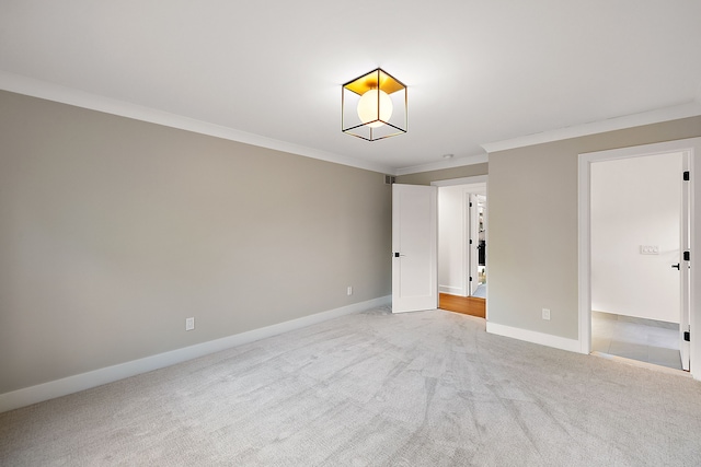 spare room with ornamental molding, baseboards, and light carpet