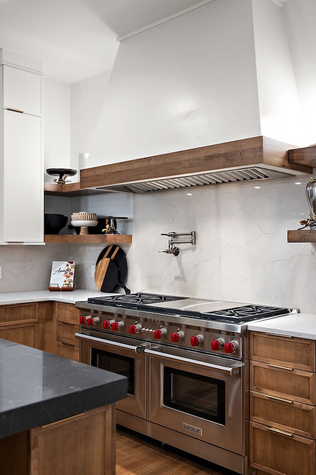 kitchen featuring open shelves, range with two ovens, decorative backsplash, white cabinets, and brown cabinets