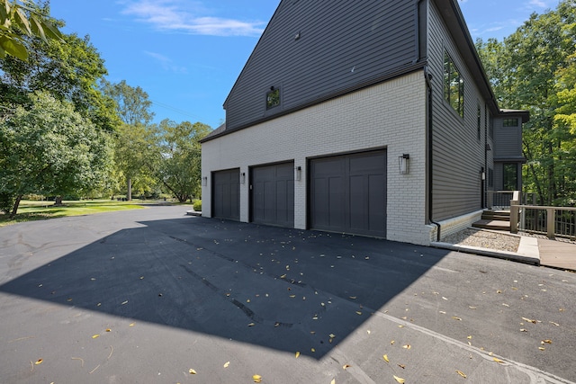 view of side of home featuring an attached garage, brick siding, and driveway