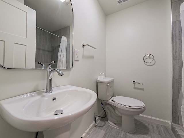 full bath featuring visible vents, toilet, a sink, curtained shower, and baseboards