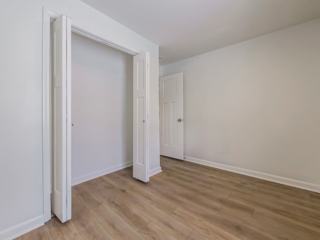 unfurnished bedroom featuring a closet, light wood-style flooring, and baseboards