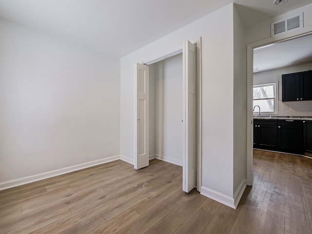 unfurnished bedroom with light wood-style floors, visible vents, and baseboards