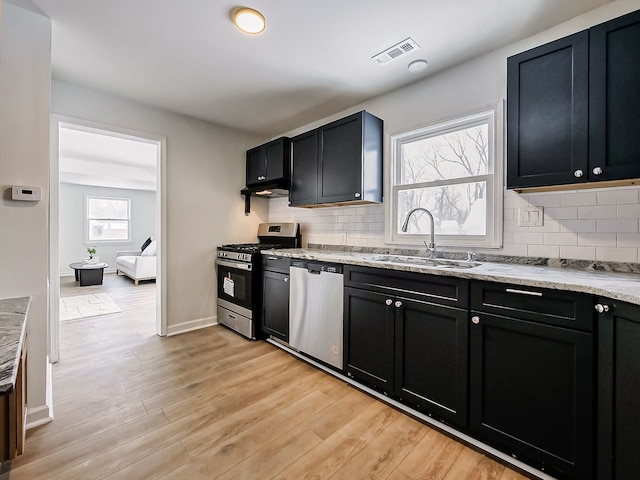 kitchen with a sink, visible vents, appliances with stainless steel finishes, and dark cabinets