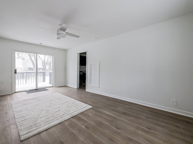 empty room featuring baseboards, dark wood-style flooring, and ceiling fan