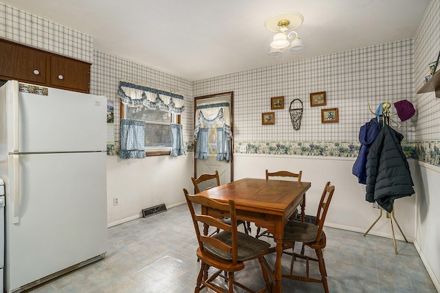 dining space featuring tile patterned floors, visible vents, wallpapered walls, and baseboards