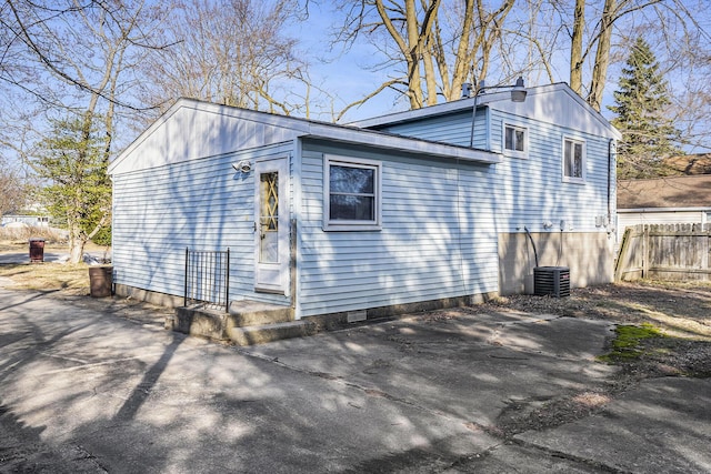 view of side of home featuring cooling unit, a patio area, driveway, and fence