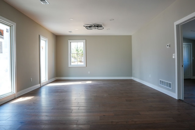 unfurnished room featuring dark wood-style floors, visible vents, and baseboards