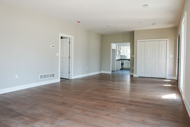 unfurnished room featuring dark wood finished floors, baseboards, and visible vents