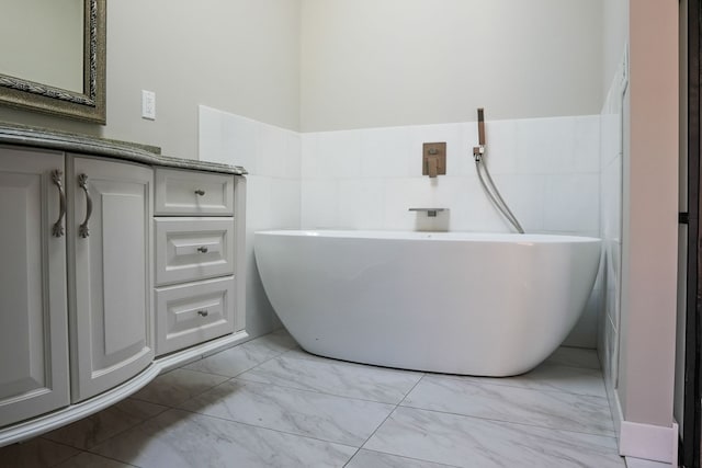 full bathroom featuring marble finish floor, a freestanding bath, and vanity