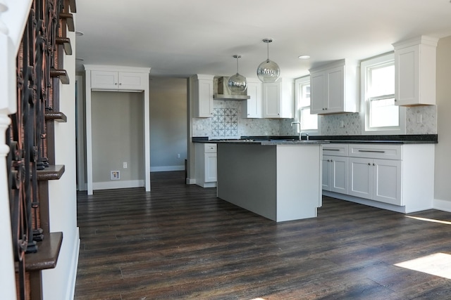 kitchen featuring decorative backsplash, dark countertops, dark wood-style flooring, and a center island