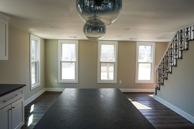 interior space featuring baseboards, plenty of natural light, and dark wood finished floors