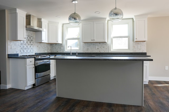 kitchen featuring white cabinetry, dark countertops, wall chimney exhaust hood, and stainless steel gas range oven