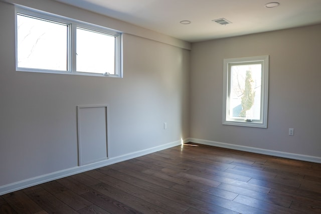 spare room featuring dark wood finished floors, visible vents, and baseboards