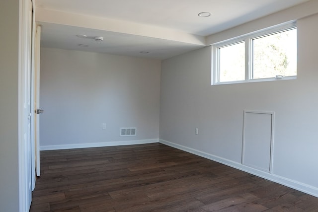 empty room with visible vents, baseboards, and dark wood-style flooring