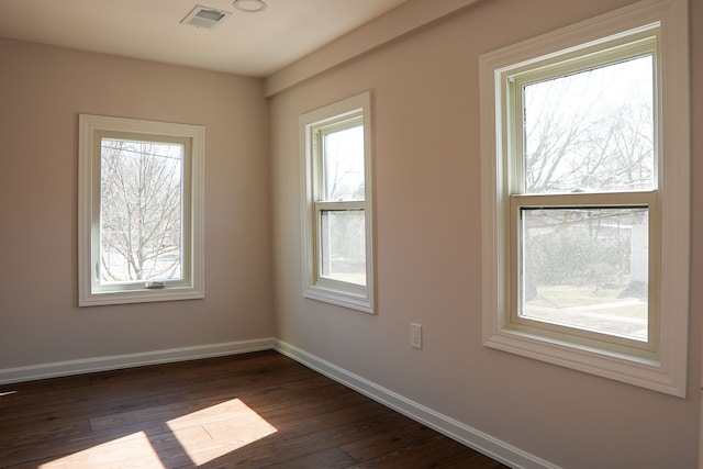 spare room with visible vents, baseboards, and dark wood-style floors