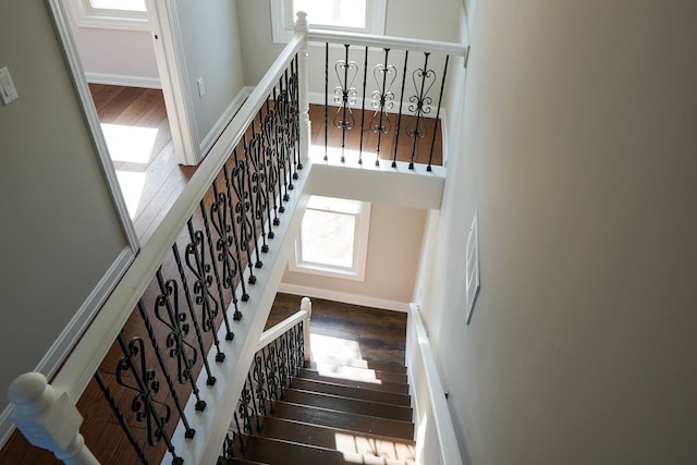 stairway featuring a high ceiling, wood finished floors, and baseboards