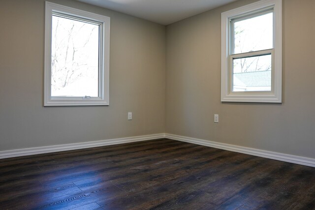 spare room featuring baseboards, plenty of natural light, and dark wood finished floors