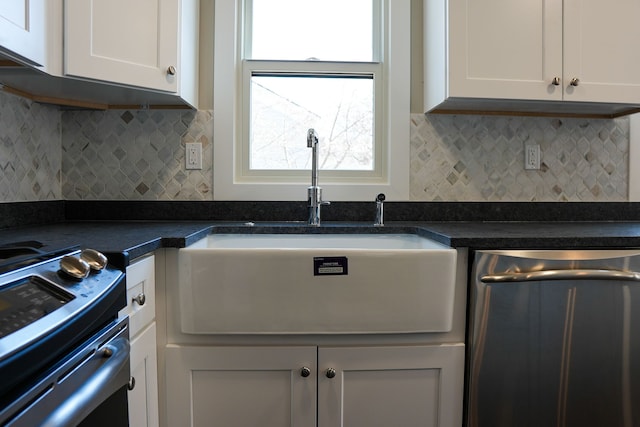 kitchen featuring a sink, tasteful backsplash, stainless steel dishwasher, dark countertops, and white cabinets