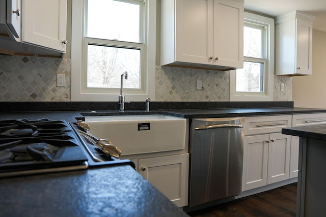 kitchen with a sink, backsplash, dark countertops, white cabinets, and dark wood-style flooring