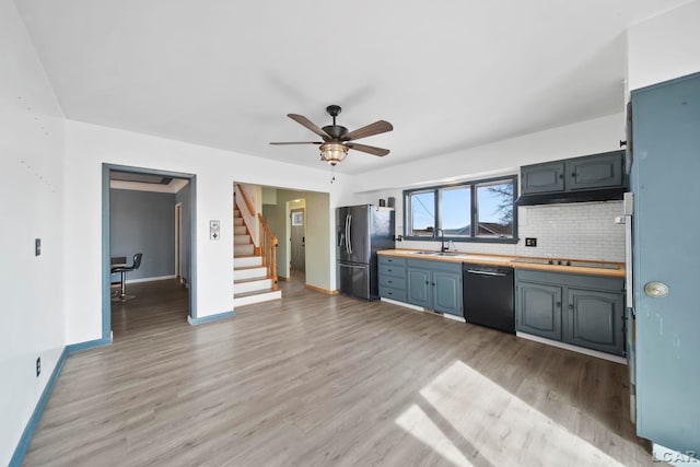 kitchen featuring light wood finished floors, baseboards, decorative backsplash, black appliances, and a sink