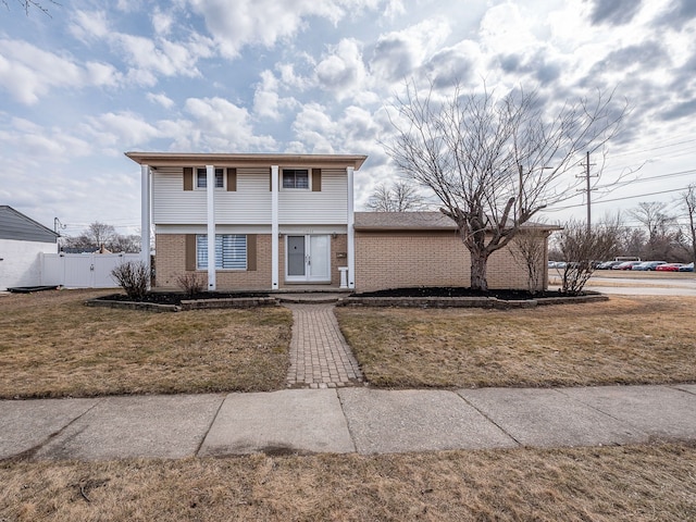 view of front of property with a front lawn, fence, and brick siding