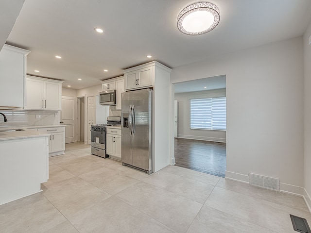 kitchen featuring white cabinets, tasteful backsplash, visible vents, and appliances with stainless steel finishes